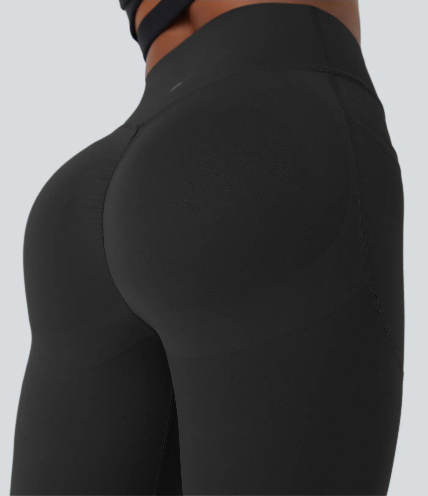Side view of model in black nylon-elastane BBL leggings showing seamless design and contour fit.
