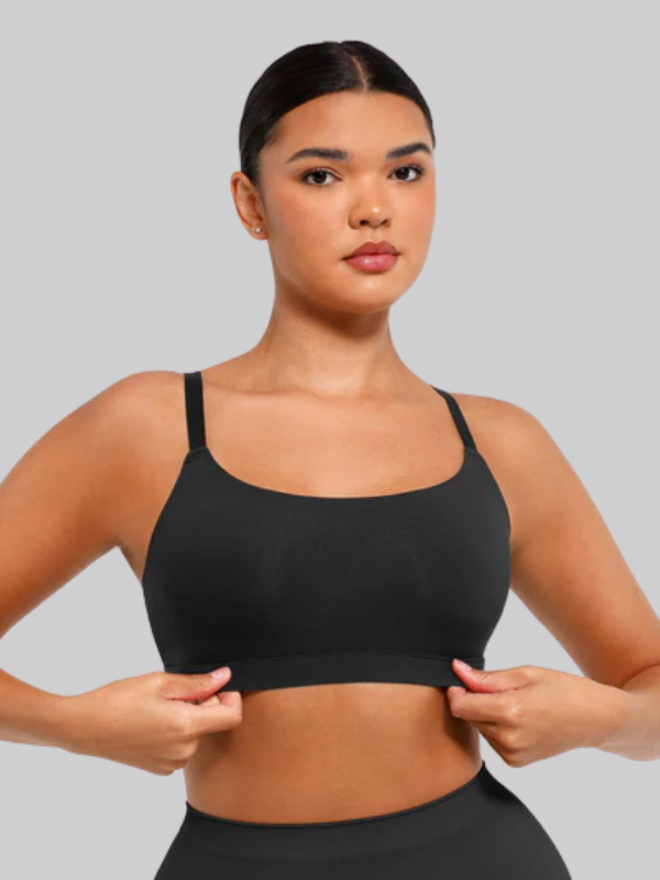 Woman adjusting a wireless black square neck bra, showcasing a smooth, seamless fit with elastic support for everyday comfort and layering.